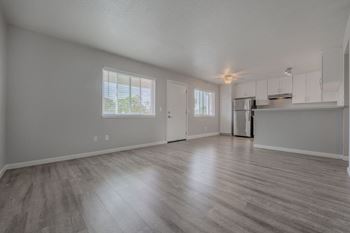 The living room and kitchen of an empty house with wood floors